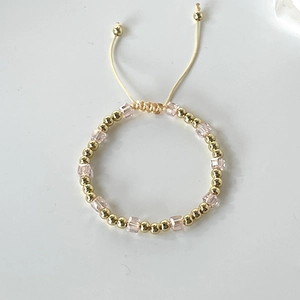 Detail view of gold beads and pink crystal cube beads on a flexible adjustable bracelet