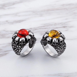 Detailed view of punk skull rings with red and yellow evil eye stones in antique silver