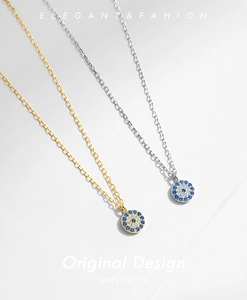 Detailed view of silver and gold evil eye pendants with sparkling blue and white zircons