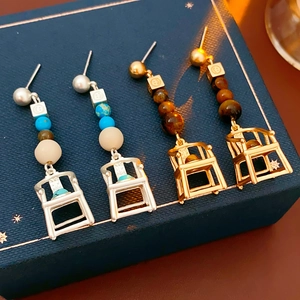 Detail of vintage high chair earrings in gold and silver with blue and brown beads