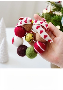 Close-up of handmade Christmas wool felt balls with metal bells and ribbon bow decoration