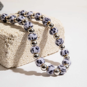 Détail de perles argentées et charms en peluche à motif animal sur un collier de Noël