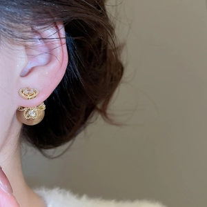Close-up of elegant gold heart earring with intricate hollowed metal pearl detail