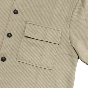 Close-up of khaki twill jacket showing fabric texture, flap pocket and black button detail