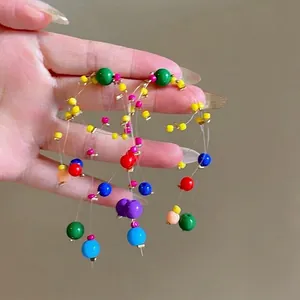 Vue détaillée des longues boucles d'oreilles à pompons avec perles colorées d'été