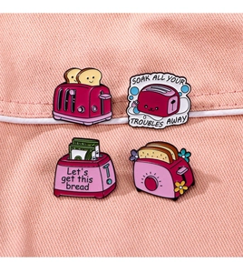 Detailansicht von vier rosa Emaille-Pins mit Toaster-Motiv auf rosa Denim-Hintergrund
