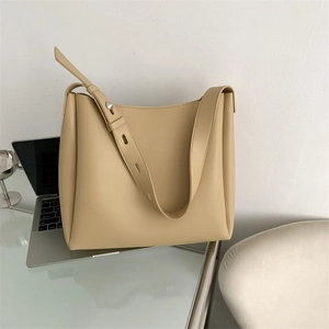 Detail of beige leather tote bag featuring a large capacity and adjustable shoulder strap