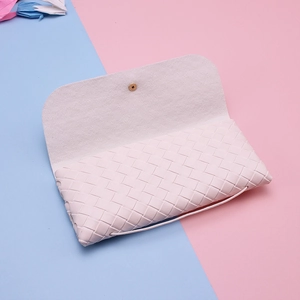 Close-up of pink woven leather eyewear case with a gold magnetic clasp and textured finish