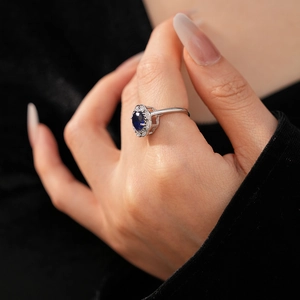 Detailed close-up of a silver ring with an oval blue gemstone and zircon floral cluster