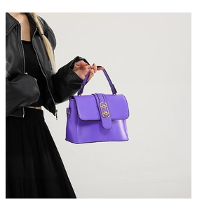 Detail of purple crossbody bag with golden oval hardware and smooth faux leather texture