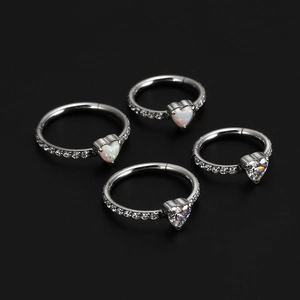 Macro shot of silver heart septum rings with opal and zircon stones on black background