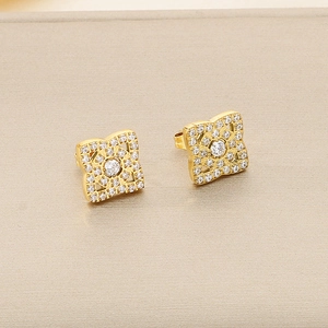 Gros plan de boucles d'oreilles fleurs dorées avec zircons blancs brillants sertis
