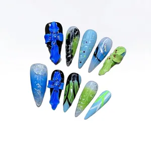 Blue stiletto press-on nails with 3D cross charms and Balinese-style hand-carved floral patterns