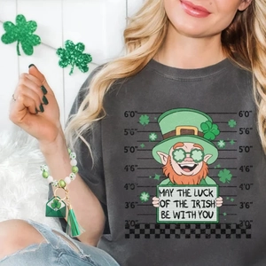 Detail of St. Patrick's Day wooden bead bracelet with clover charm and green tassel on wrist