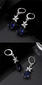 Macro shot of silver teardrop earrings with blue pear-cut stone and zircon floral detail