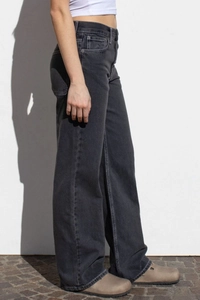 Detail view of high waist wide leg jeans in washed dark grey denim on a model