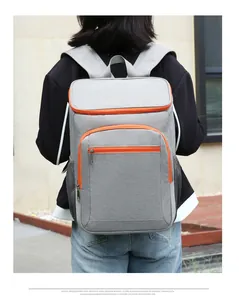 Rear view of a grey outdoor picnic cooler backpack with orange zippers on a person