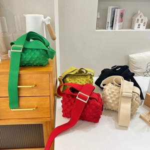 Detail of five colorful bubble knit crossbody bags with textured fabric and wide straps