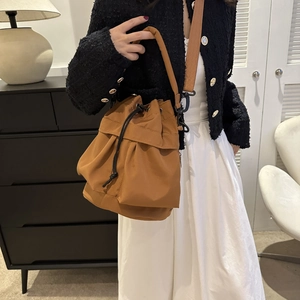 Détail du sac seau marron en nylon avec cordon de serrage et bandoulière large marron