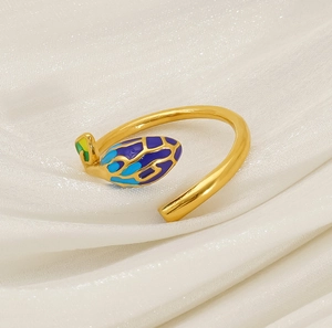 Detail of gold open ring featuring vibrant blue and green enamel leaf wing design