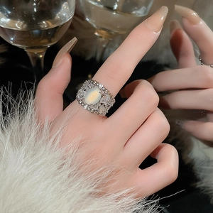 Detail of luxury oval opal ring with zircon pavé on hand with cocktail glass and fur