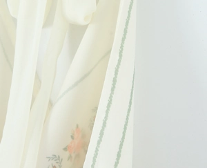Detailed macro texture of ivory floral satin fabric with orange petals and green wavy stripes