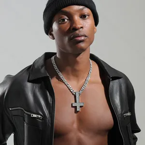 Close-up of iced-out inverted cross pendant with cuban chain on male model in leather jacket