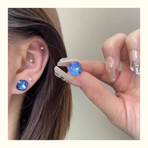 Macro detail of blue cushion-cut crystal earring with flat back screw on the ear