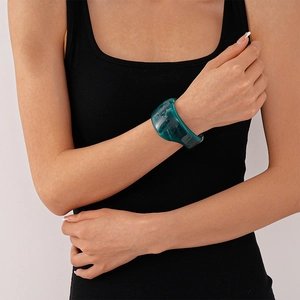 Detailed view of wide teal translucent resin cuff bracelet worn by a model