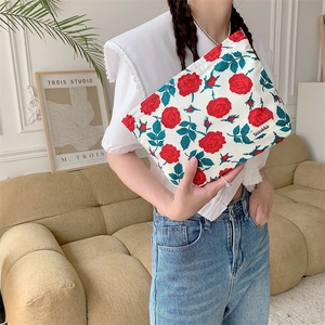 Detail of vintage floral makeup bag held by model featuring retro rose prints and zipper