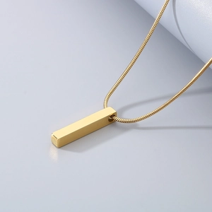 Detail of a polished gold rectangular pendant on a fine snake chain necklace