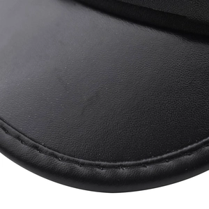 Macro di pelle nera con trama a grana fine e cuciture pulite sul dettaglio della visiera