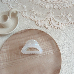 Close-up of iridescent acetate hair claw clip on wooden tray and lace background