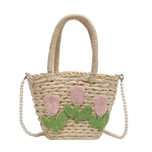 Stroh-Eimertasche mit rosa Häkeltulpen und Perlenkette auf schlichtem weißem Grund
