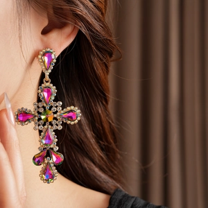 Close-up of vintage gold cross earrings with colorful rhinestones on a female model