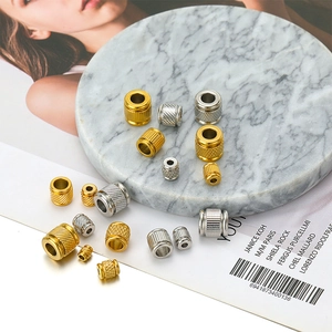 Detailed view of silver and gold textured stainless steel cylinder beads on marble