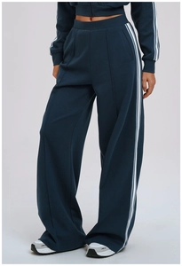 Close-up of high-waist wide-leg track pants featuring white side stripes and front pleats