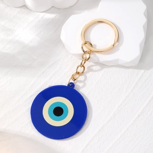 Dettaglio del ciondolo occhio blu con catena dorata su una superficie bianca testurizzata