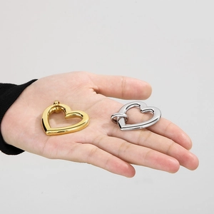 Detail of gold and silver heart-shaped 18K gold-plated spring clasps held by hand