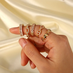 Adjustable brass rings in gold with zircon stones shown on fingers over silk fabric
