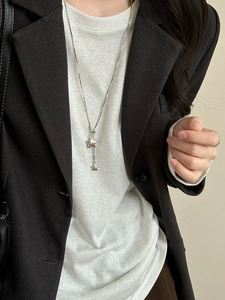 Close-up of a silver Y-shaped long necklace featuring two star pendants on a model