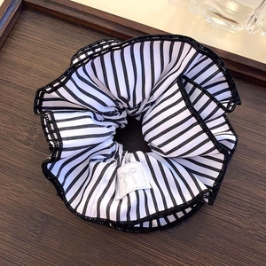 Gros plan du chouchou en dentelle à rayures noires et blanches sur plateau en bois