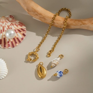 Golden sea shell and blue ceramic bead charm bracelet on natural driftwood display
