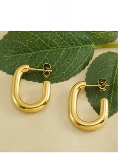 Macro shot of 18k gold plated U-shaped earrings on leaf with butterfly clasp closure