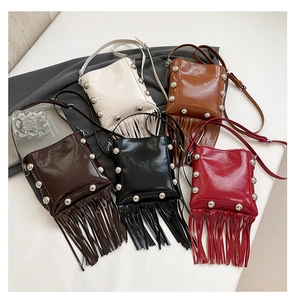 Detail of five crossbody tassel bags in white, brown, coffee, black, and red colors