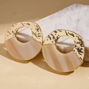 Detail of irregular round acrylic earrings with gold hammered metal and beige resin