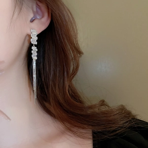 Close-up of elegant silver tassel earrings with rectangular cubic zirconia stones on model