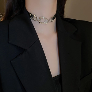 Gros plan d'un choker en similicuir noir avec métal argenté irrégulier et perle d'eau