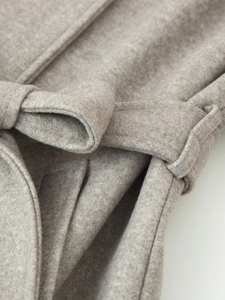 Detail shot of the tied belt and soft wool texture on a grey winter coat for women