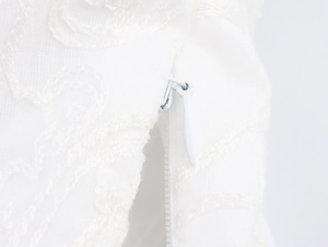 Détail macro d'une fermeture éclair invisible sur haut court blanc en dentelle brodée